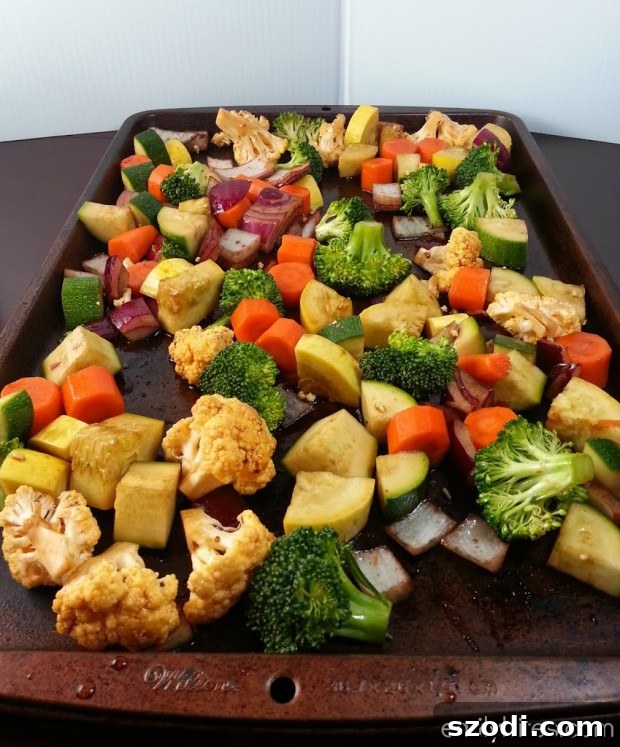 Raw, pre-cooked vegetables tossed with balsamic and olive oil on a baking sheet