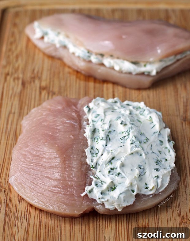 Raw chicken breast butterflied open, ready for the cream cheese and herb filling.