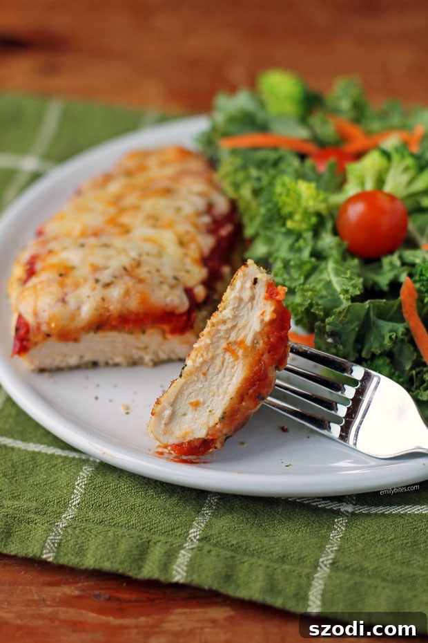 Close-up of a bite of Chicken Parmesan on a fork, showcasing the crispy coating, melted cheese, and rich sauce.