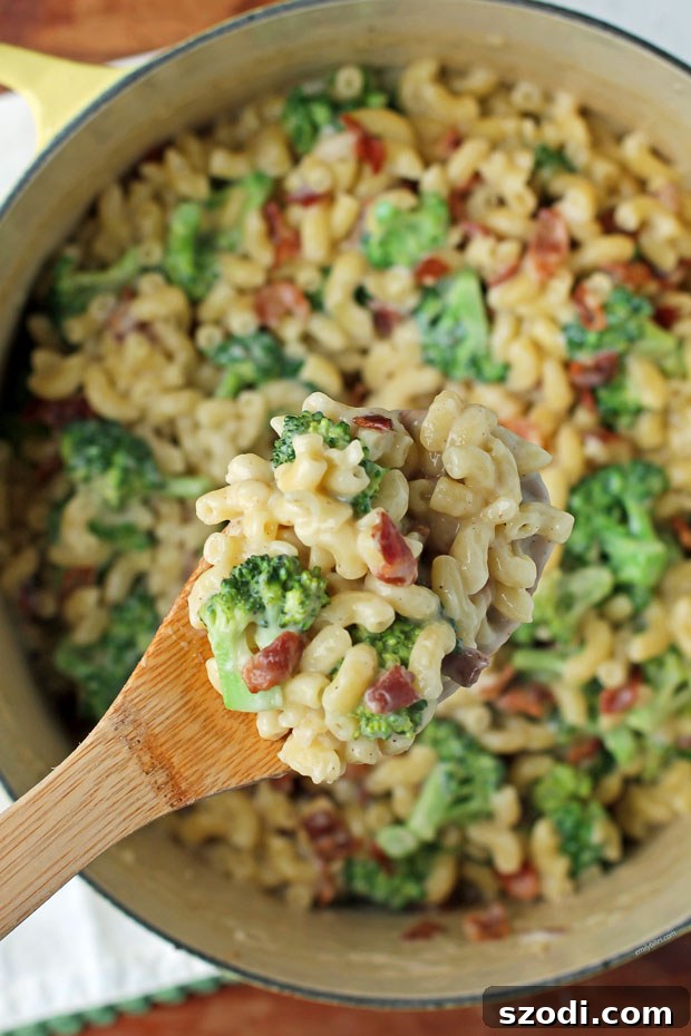 A spoonful of creamy One-Pot Bacon Broccoli Mac and Cheese, showcasing the rich sauce, pasta, bacon, and broccoli.