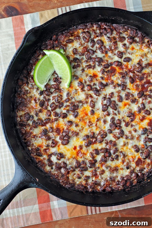 Bold Spicy Black Bean and Cheese Skillet 2 Cheesy Spicy Black Bean Skillet with fresh lime wedges, vibrant and inviting