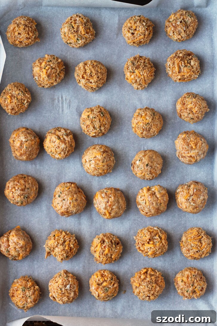 Raw Bisquick Chicken Sausage Balls mixture rolled into uniform balls on a baking sheet, before cooking