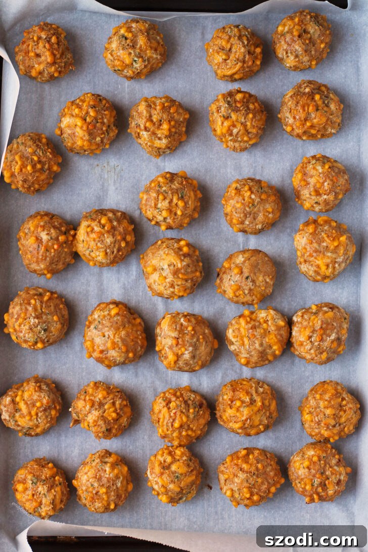 Golden brown Bisquick Chicken Sausage Balls cooked to perfection on a baking sheet, with cheese visibly bubbling