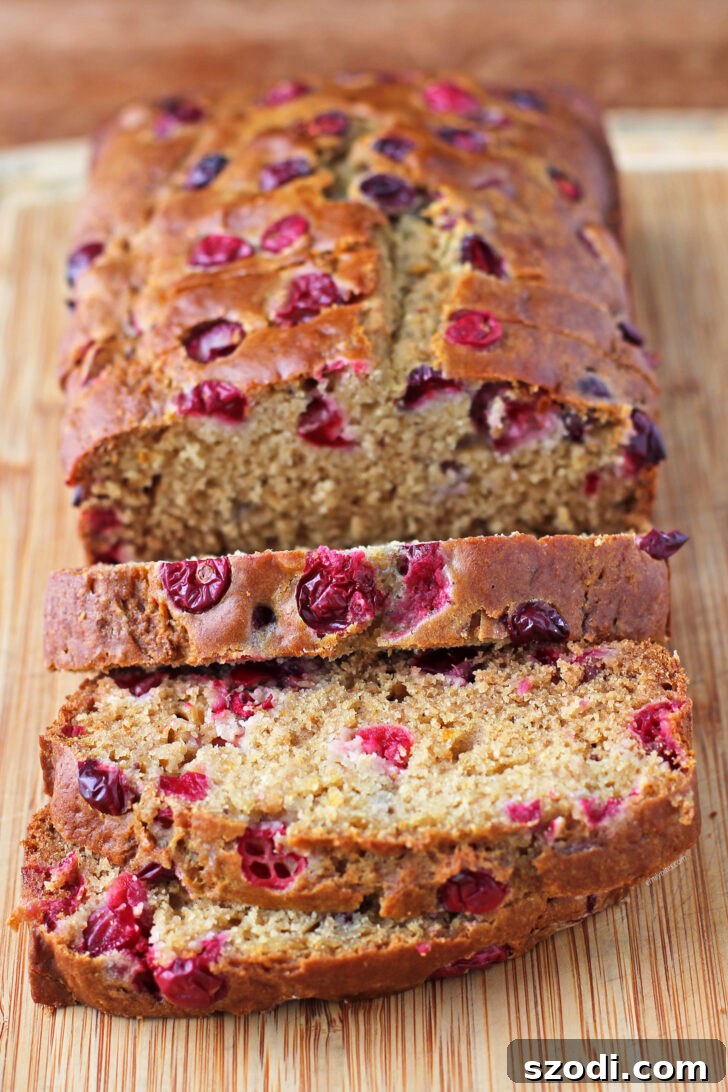 Deliciously sliced Orange Cranberry Bread on a rustic cutting board, ready to be enjoyed.