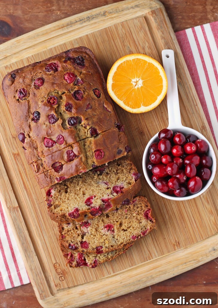 Ingredients for Orange Cranberry Bread laid out on a table, including oranges, cranberries, flour, and a mixing bowl.