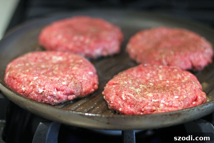 Stuffed Pizza Burgers sizzling on a stovetop grill pan, achieving a perfect sear.
