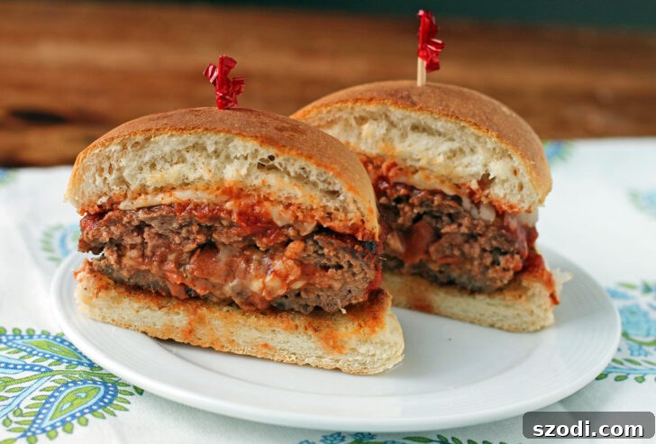 Close-up of a Stuffed Pizza Burger, sliced open to reveal the perfectly melted Mozzarella, rich pizza sauce, and savory pepperoni filling.